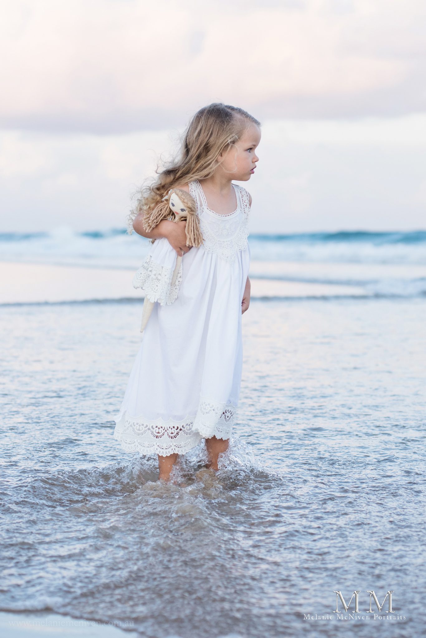 girl standing in water with doll